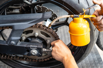 Motorcycle mechanic check motorcycl chain for wear and  stretch and use gear oil to lube chain Maintenance and repair motorcycle concept