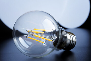 Modern transparent LED filament lamp with yellow threads on a dark background. Saving electricity....