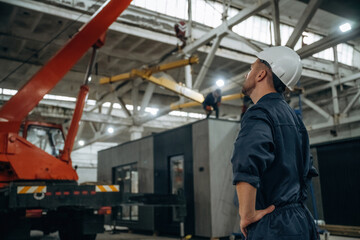 Male worker is in the modern warehouse or manufacturing company