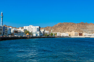 Fototapeta premium Coastal view of Muscat Oman highlighting the waterfront and historic architecture under a clear blue sky