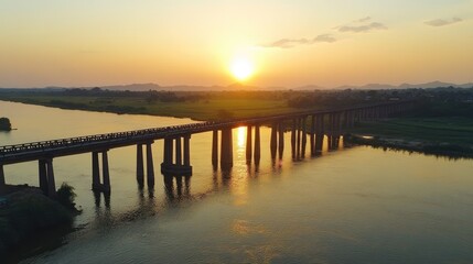 Fototapeta premium Sunset Over Water with Bridge Silhouette