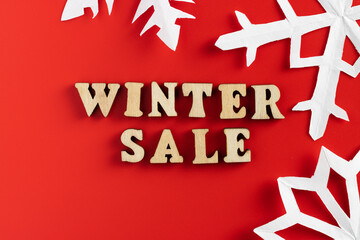 winter sale wording with paper cut out snowflakes on red background. selective focus