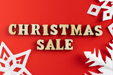 christmas sale wording with paper cut out snowflakes on red background. selective focus