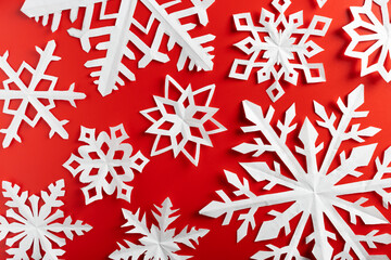 white paper cut out snowflakes in red background. winter or christmas theme background. selective focus.