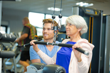 physiotherapist watching senior woman use weights equipment
