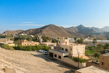 Bahla Fort overlooking the desert landscape in Oman showcasing ancient architecture and nearby town during a sunny day