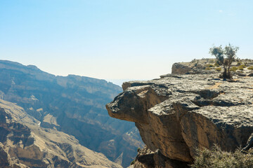 Spectacular rocky landscape in Oman showcasing dramatic cliffs and deep valleys under a clear blue...