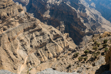 Fototapeta premium Explore the breathtaking landscapes of Oman with dramatic cliffs and rugged terrains overlooking deep canyons at midday