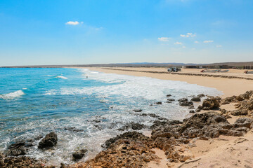 The serene coastline of Oman with gentle waves lapping on sandy beaches under a bright blue sky