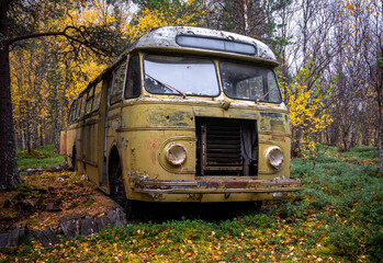 An old, abandoned, rusty bus left in the forest of Northern Norway. Magic bus. Seasonal scenery of Scandinavia.