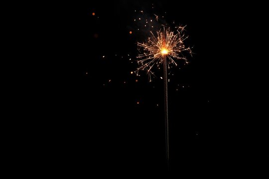 A close-up shot of a sparkler against a dark background - Powered by Adobe