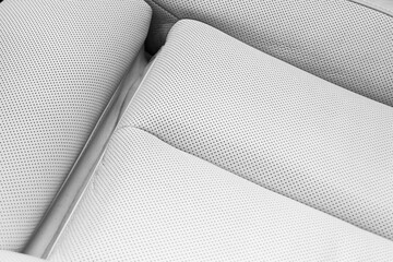 White leather interior of the luxury modern car. Perforated white leather comfortable seats with stitching. Modern car interior details.