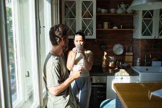 Couple talking in the kitchen at morning with coffee - Powered by Adobe