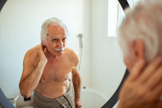 Senior man looking at himself in the bathroom mirror