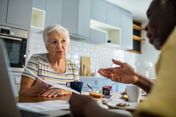 Senior couple discussing bills at kitchen table