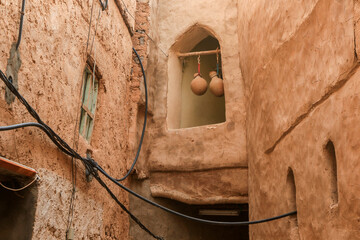Charming narrow alley in an Omani village featuring traditional architecture and hanging pottery in the afternoon light