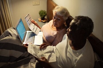 Senior couple discussing medical bills in bed at night