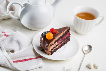 Delicate and delicious chocolate cake with butter cream and berries on a white table