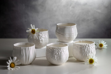 Porcelain white cups with chamomile flowers on a light table