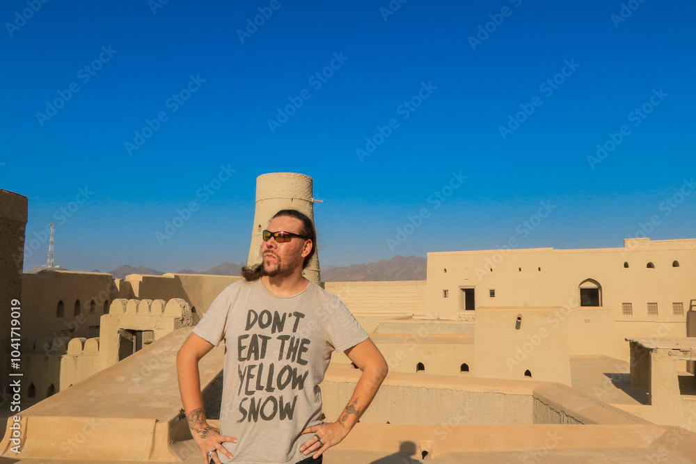 Wall mural a tourist exploring the stunning architecture of oman while enjoying breathtaking views from a histo