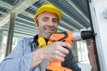 a man drilling a window frame