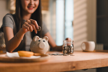 Saving money can be rewarding experience, as shown by woman happily depositing coins into piggy...