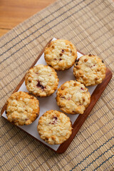 muffins arranged on a wooden board with a white paper underneath.