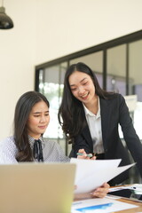 Group of happy Asian business people having a meeting at the office. Two women working together using modern laptops.