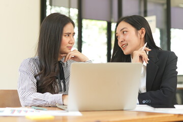 Group of happy Asian business people having a meeting at the office. Two women working together using modern laptops.