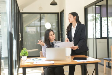 Two businesswomen are considering documents in an office.