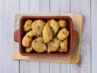 Breaded chicken bites in a plate over wooden table