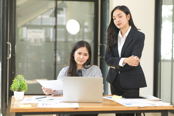 Happy Asian business people working together using laptop and tablet in office.