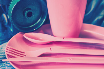 Overlock.Pink plastic dinnerware set in tailor workshop.Cup,fork,knife,spoon
