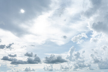 Fluffy white clouds drift across a bright blue summer sky