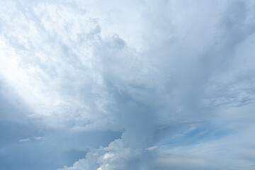 Fluffy white clouds drift across a bright blue summer sky