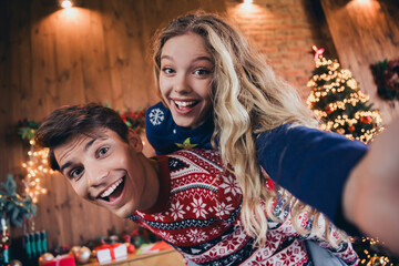 Photo of nice young couple take selfie photo piggyback wear christmas clothes enjoy cozy x-mas party decoration interior flat indoors