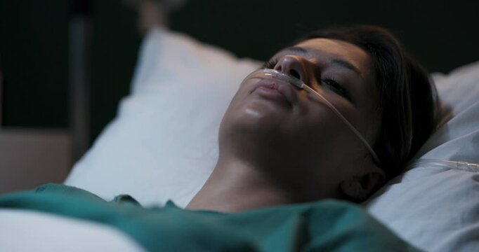 Patient resting in hospital room with nasal oxygen tubing.