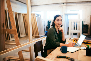 Laptop, notebook and portrait with carpenter woman in workshop for craftsmanship, joinery or...