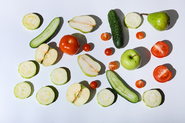 Variety of vegetables and fruits cut on halves and whole placed on white background with hard...