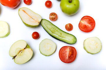 Variety of vegetables and fruits cut in halves, sliced zucchini and whole placed on white background top view close-up