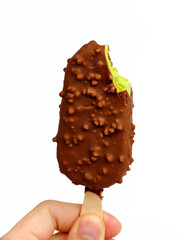 A man holding a green tea ice cream bar coated in chocolate with a bite taken out.