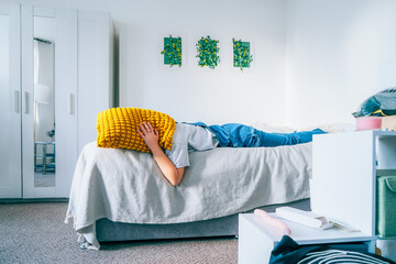 Depressed woman covering head with pillow, feels furious exhausted exasperated laying on bed. mad...