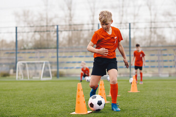 Boy Soccer Player In Training. Boy Running Between Cones During Practice in Field on Sunny Day. Young Soccer Players at Speed and Agility Practice Session