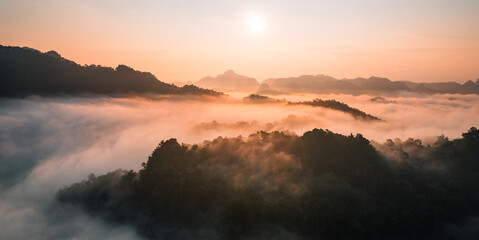 Aerial View of Morning fog and mountains as the sun rises from above