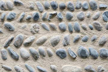 Background of a natural round river stone masonry wall with cement in Southern France. Detailed stone texture image in beige, brown, blue and grey