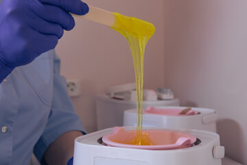 Waxing procedure with pink wax in a beauty salon during afternoon hours