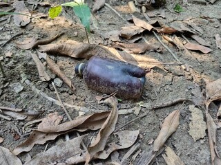 Naklejka premium A dark amber color half burned plastic bottle showing air water and soil pollution, causing climate change and bad for our environment, earth, nature