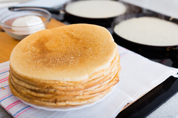 Process of baking pancakes in pans on kitchen stove. stack of hot pancakes