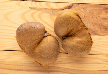 Two ripe juicy kiwis on a wooden table, macro, top view.