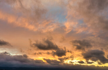A beautiful sky tinted by the sun leaving vibrant shades of gold, pink, blue and multicolored. Clouds in the twilight evening and morning sky. Cloudy sky background in the evening, and during the day.